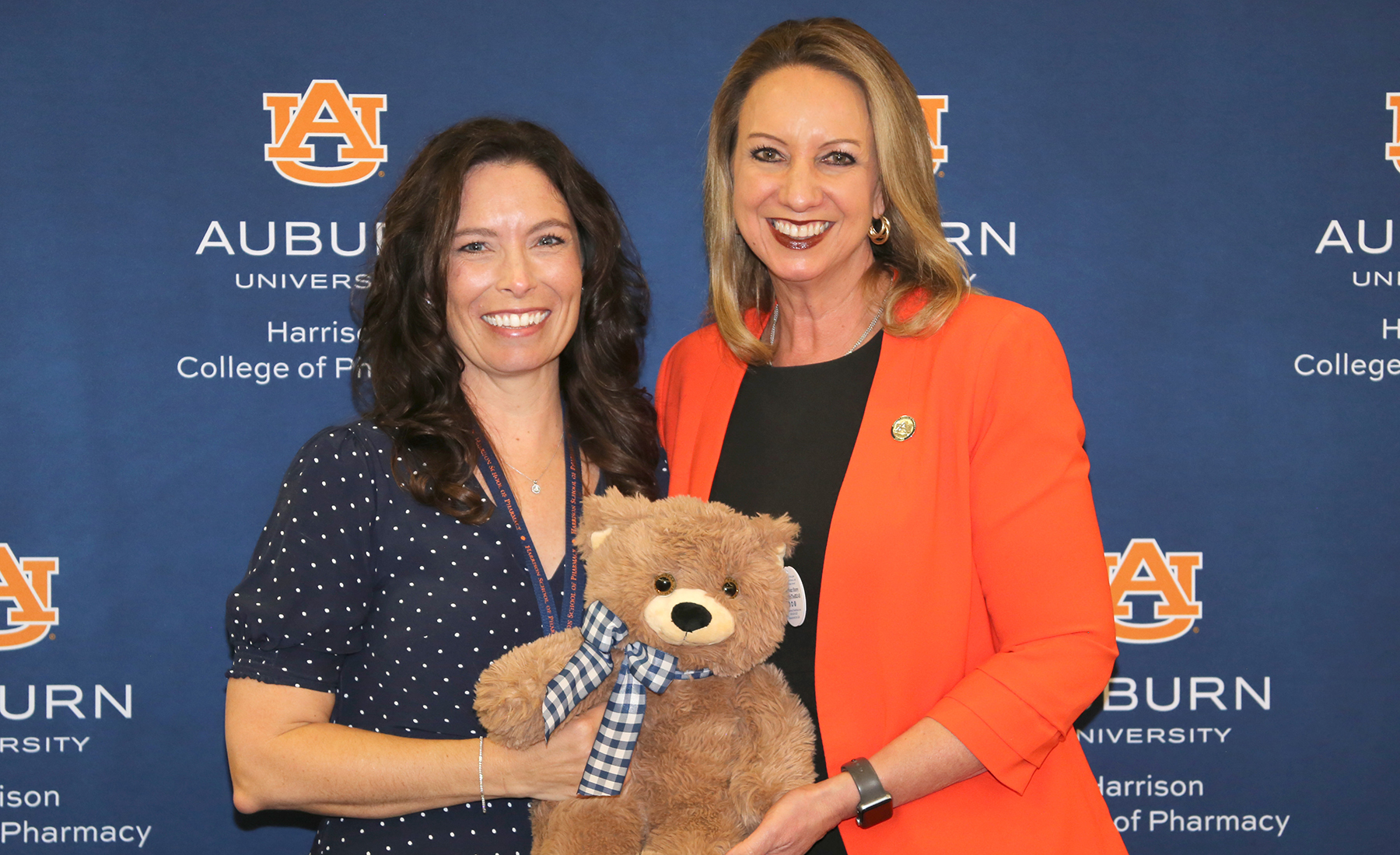 Two people stand holding a teddy bear